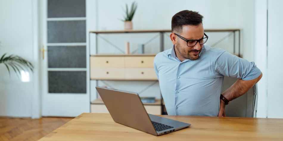 A man having back pain at work while working from home