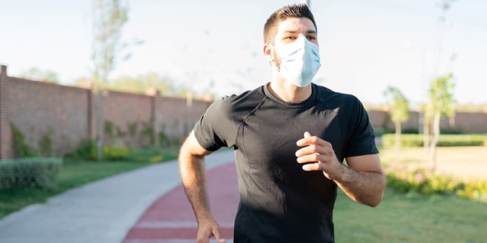 A person wearing a mask jogs along a
    path.