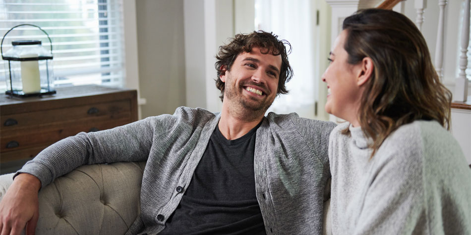 two people talking and laughing while sitting on a couch