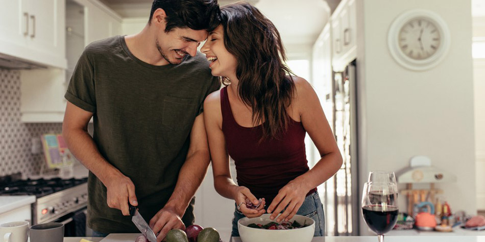 A young couple prepares fresh fruits and veggies for a healthy meal at home.