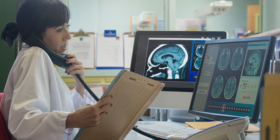 doctor examining a brain scan on a computer screen
