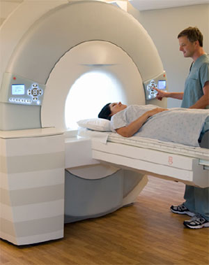woman inside an MRI scanner with a technician standing beside her